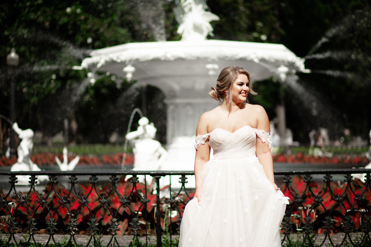 A bride stands by the white fountain at her Forsyth Park Wedding, Savannah GA