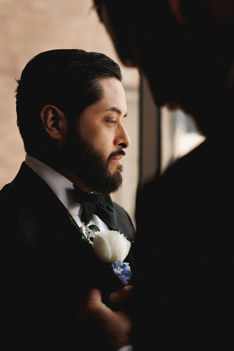 A groom has his boutonniere pinned to his lapel