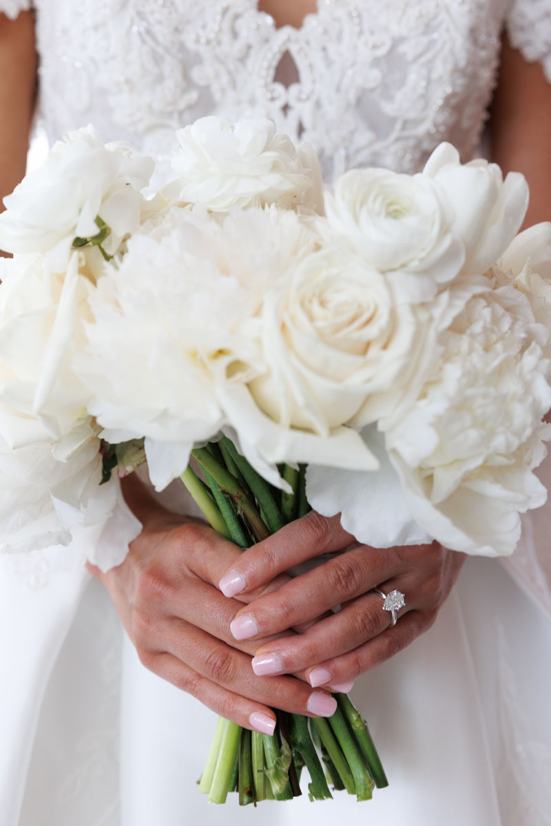 A bride's hands holding a bouquet of white flowers