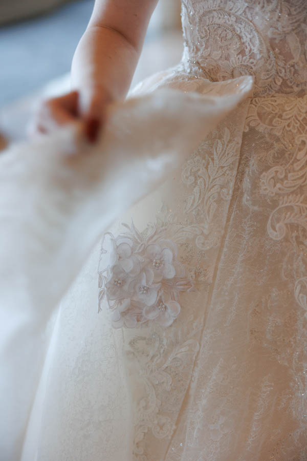 The bride shows a dress detail, sewn into the dress is a part of her mother's wedding gown