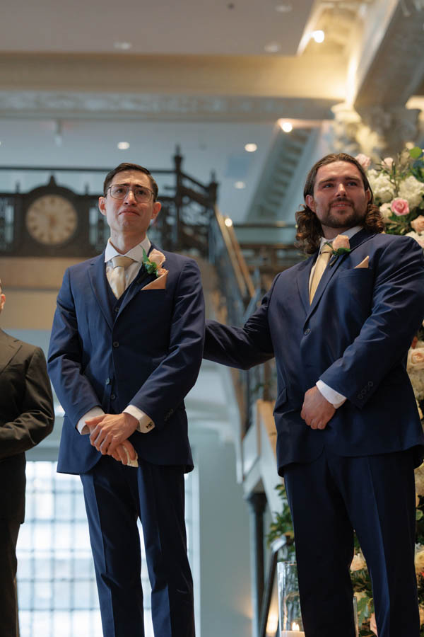 The best man supports the groom as the bride arrives