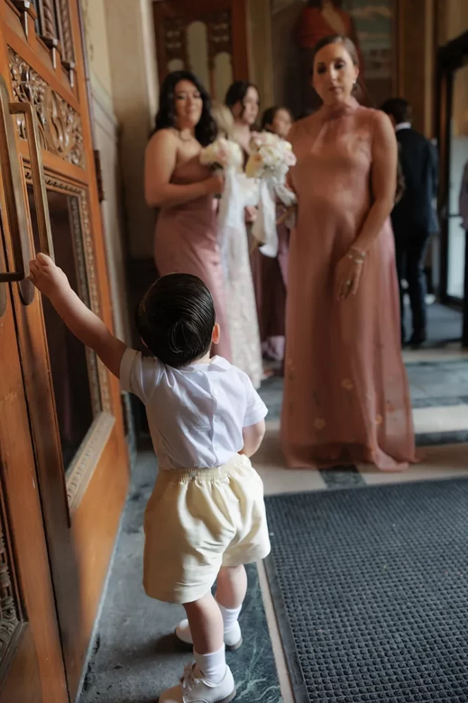 The flower boy tries to open the heavy church door