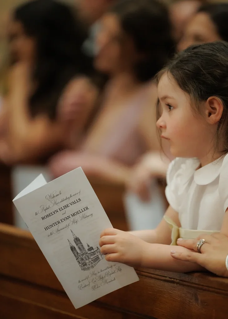 The flower girl holds the program at a catholic church wedding