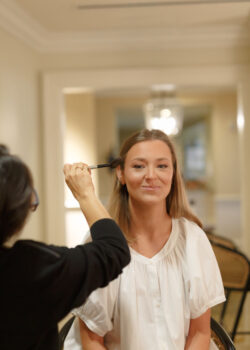 The bride smiles in the hair and makeup chair at River Oaks Country Club before her wedding