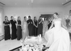 The bride shows off her dress to bridesmaids
