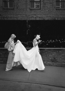 The bride walks outside the club with her Mom carrying the train