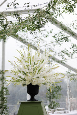 Florals by Bergner & Johnson sit atop custom wedding furniture in the tent