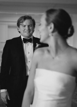 The groom approaches the bride, black and white