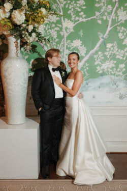 A bride and groom portrait in front of the iconic green and white wallpaper at River Oaks Country Club in Houston, Texas