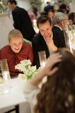 Wedding guests laugh over dinner together at River Oaks Country Club