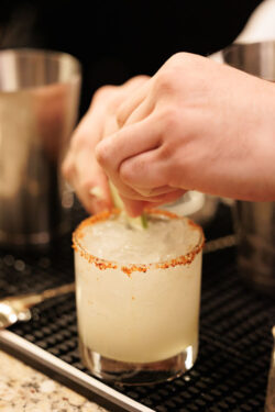 A barman garnishes a custom cocktail