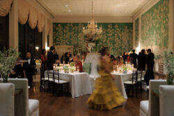 A wedding guests strides across the room with motion blur at dinner during a wedding at River Oaks Country Club