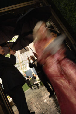 A guest hurries through rain for dinner, with motion blur (shutter drag)