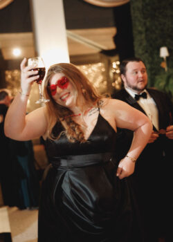 A guest dances, wearing the reception's signature red heart sunglasses