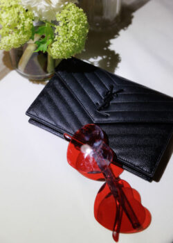 An editorial style photograph of guest fashion, a purse with the reception's signature red sunglasses