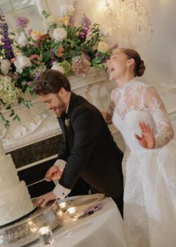 The bride laughs as the groom cuts the cake at Houston Country Club
